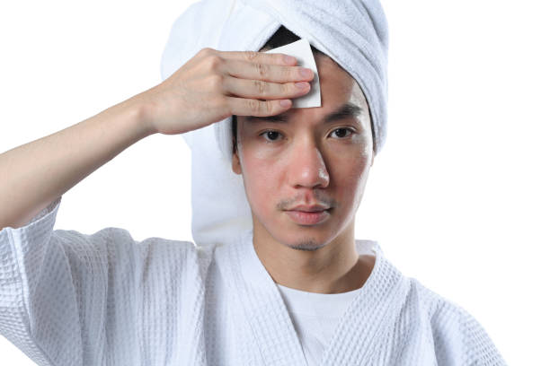 Young man cleaning his face using cotton pads and cleansing product 