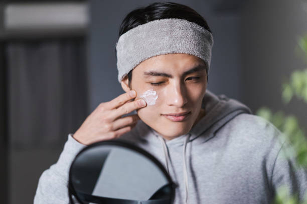 Sun damage men, applying solar defence sunscreen to the face